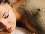 Woman lying on a massage table receiving a massage, clay body wrap