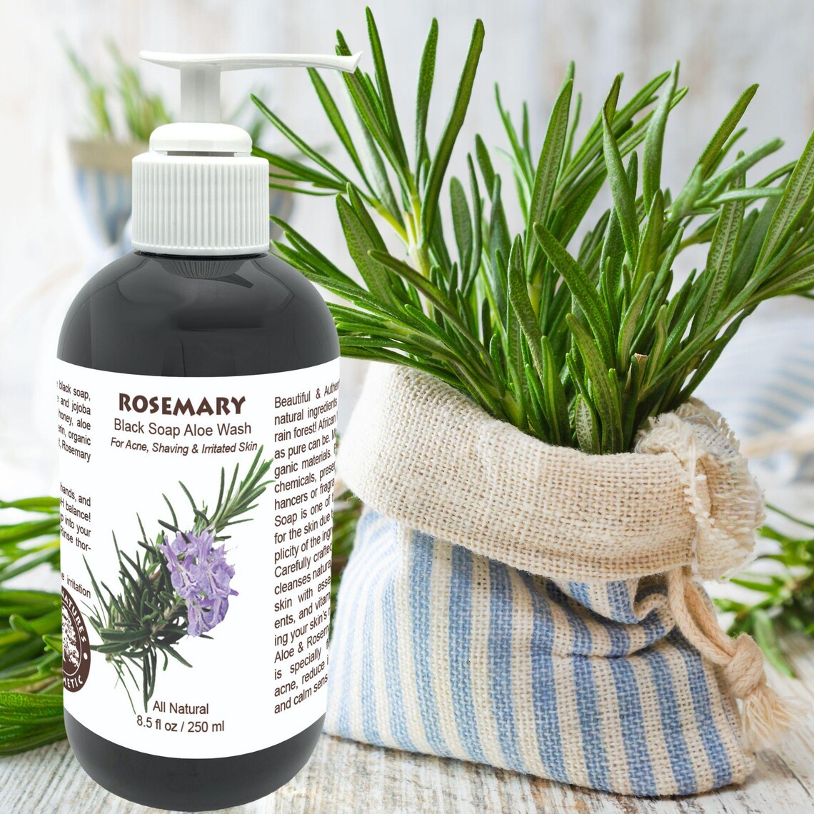 Black soap aloe wash bottle with rosemary label next to a plant and striped cloth on a light background